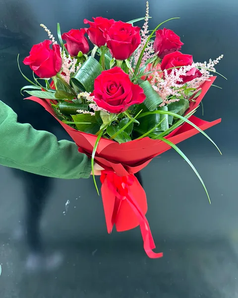 Bukiet okolicznościowy z czerwonymi różami: Elegancki bukiet z dużymi czerwonymi różami, uzupełniony delikatną różową astilbą i zielenią dekoracyjną, zapakowany w czerwony papier. Kwiaciarnia Bukieteria Gorzów Wielkopolski