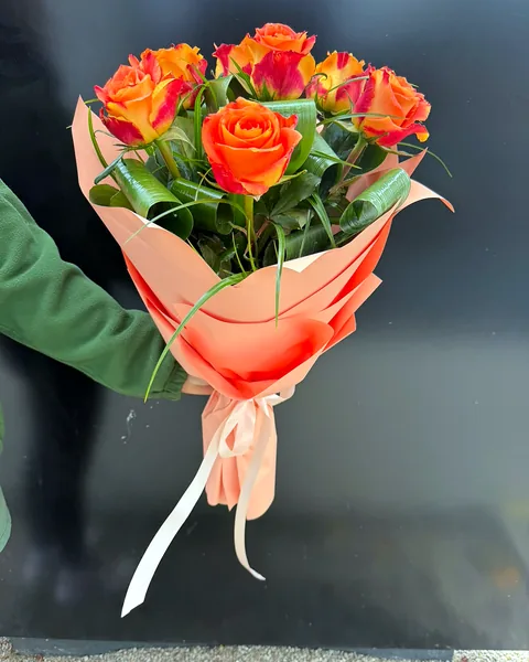Bukiet róż pomarańczowo-czerwonych: Elegancki bukiet z róż w odcieniach pomarańczu i czerwieni, opakowany w łososiowy papier. Kwiaciarnia Bukieteria Gorzów Wielkopolski