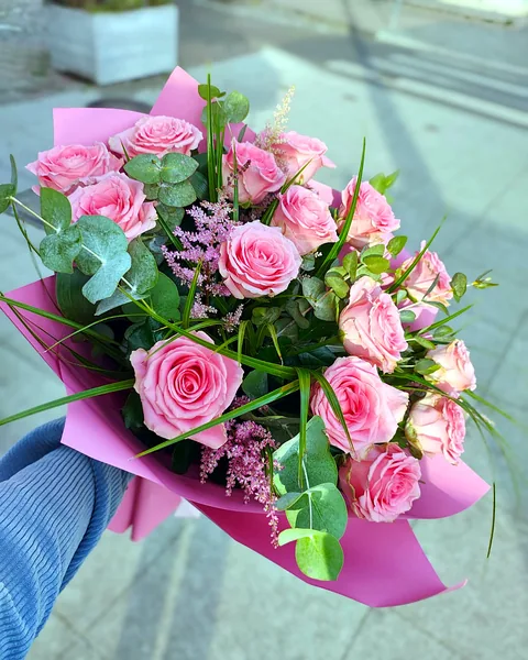 Bukiet z różowych róż: Bukiet różowych róż z pudrową astilbe, eukaliptusem i trawą ozdobną, zapakowany w różowy papier. Kwiaciarnia Bukieteria Gorzów Wielkopolski
