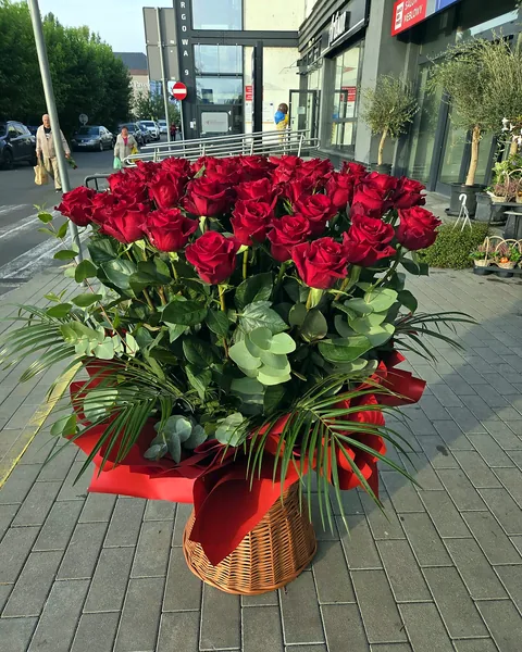 Kosz z 50 czerwonymi różami 90cm: Wiklinowy kosz wypełniony 50 czerwonymi różami o długości 90 cm, uzupełniony eukaliptusem, liśćmi palmy i czerwoną papierową dekoracją. Kwiaciarnia Bukieteria Gorzów Wielkopolski