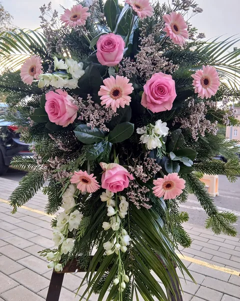 Wiązanka pogrzebowa różowy mix: Wiązanka pogrzebowa z różowymi różami i gerbera, białymi kwiatami, zielenią i dekoracyjnymi gałązkami. Kwiaciarnia Bukieteria Gorzów Wielkopolski