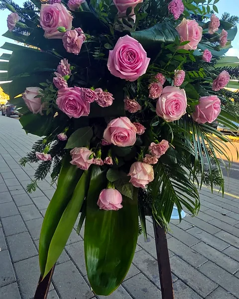 Wiązanka pogrzebowa w odcieniach różu: Wiązanka pogrzebowa z różowymi różami, goździkami i zielenią palmową, utrzymana w delikatnej tonacji różu. Kwiaciarnia Bukieteria Gorzów Wielkopolski