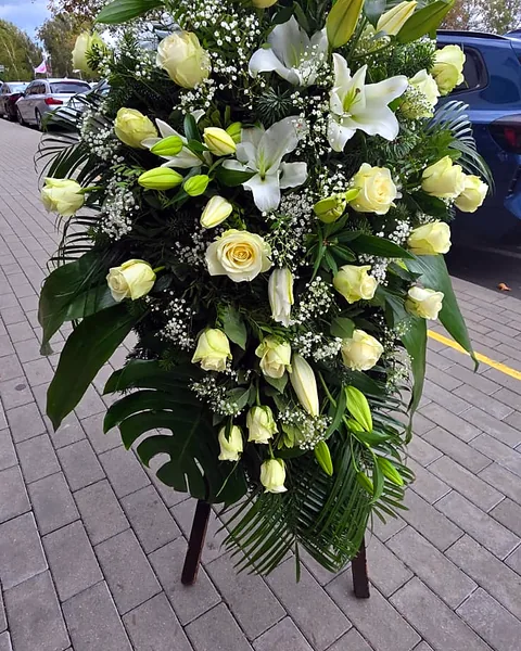 Wieniec żałobny z białymi różami i liliami: Elegancki wieniec żałobny z białymi różami, liliami i gipsówką, utrzymany w klasycznej, białej kolorystyce. Kwiaciarnia Bukieteria Gorzów Wielkopolski